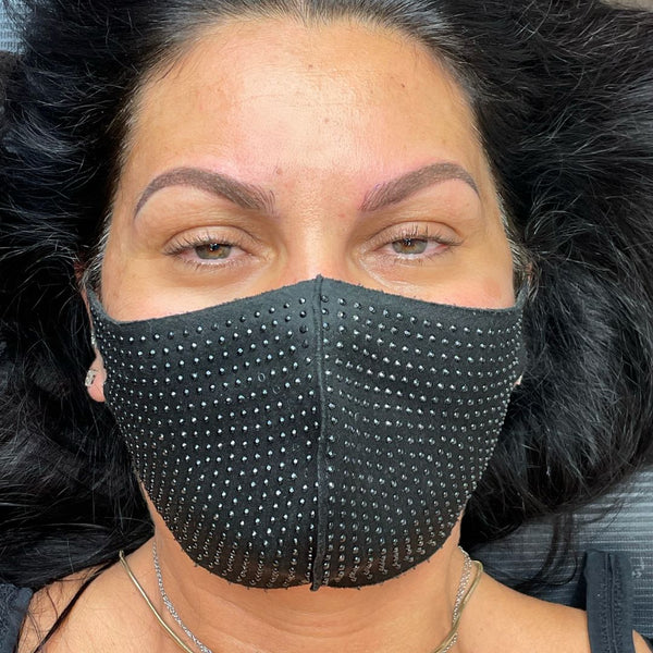 Woman with combination brows done wearing a black face mask with silver embellishments in Grimsby clinic